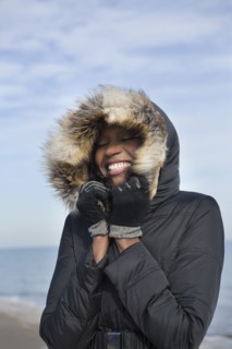 Smiling woman wearing coat on beach