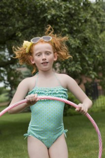Caucasian girl jumping with plastic hoop in field