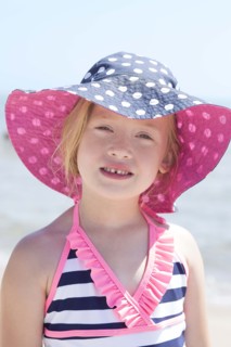 Caucasian girl wearing sun hat and bathing suit on beach