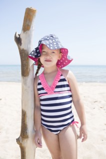 Caucasian girl leaning on wooden pole on beach