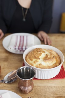 Girl sitting near baked souffle on table