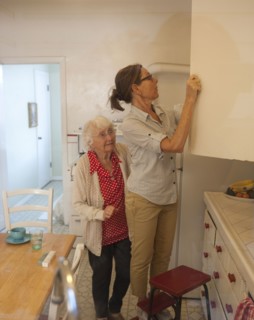 Caregiver reaching in cabinet for older woman