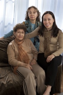Three generations of women smiling on sofa