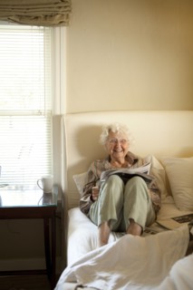 Older Caucasian woman reading newspaper in bed
