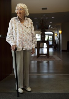 Older Caucasian woman standing with cane in retirement home