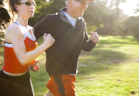 Caucasian man running with trainer in field