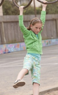 Caucasian girl playing on monkey bars at playground