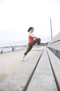 Caucasian woman stretching on beach bench