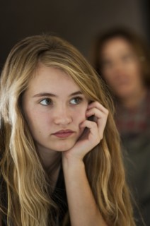 Serious teenage girl examining herself in mirror