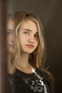 Serious teenage girl examining herself in mirror