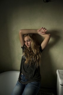 Serious teenage girl sitting in bathroom