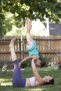 Mother and daughter practicing yoga in backyard