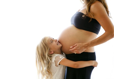 Caucasian girl hugging pregnant mother