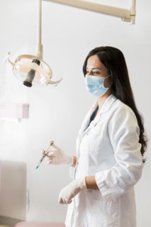 Indian dentist holding syringe near lamp