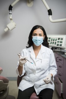 Indian dentist holding syringe in office