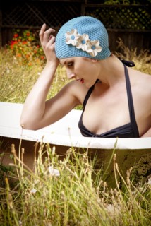 Woman wearing vintage swim cap in bathtub in backyard