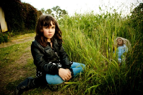 Girl playing with doll in tall grass