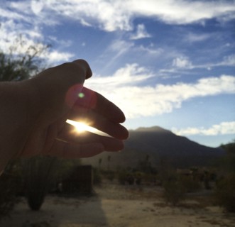 Close up of hand obscuring sunlight in field