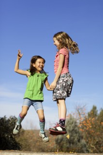 Girls jumping for joy on stone wall