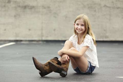 Smiling girl wearing cowboy boots in parking lot