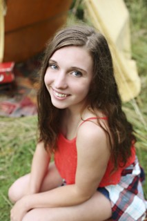 Smiling woman crouching at camping tent