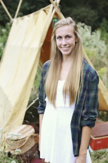 Smiling woman standing at camping tent