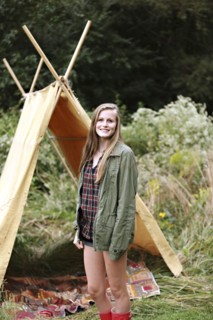 Smiling woman standing at camping tent
