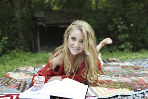 Teenage girl drawing in notebook on blanket