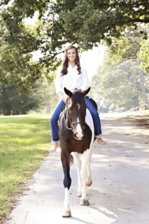 Woman riding horse on dirt road
