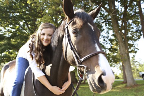 Woman hugging horse in rural field