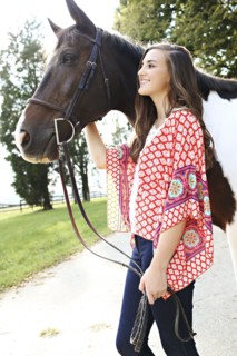 Smiling woman walking horse on dirt path