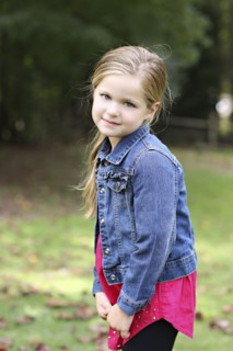 Serious girl standing in rural field