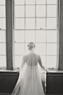 Bride in veil and wedding gown standing at window