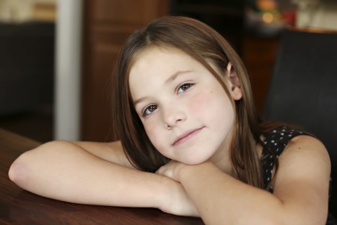Close up of serious girl resting chin on hand