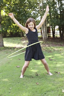 Smiling girl playing with plastic hoop in field