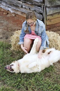 Caucasian girl scratching belly of dog on farm