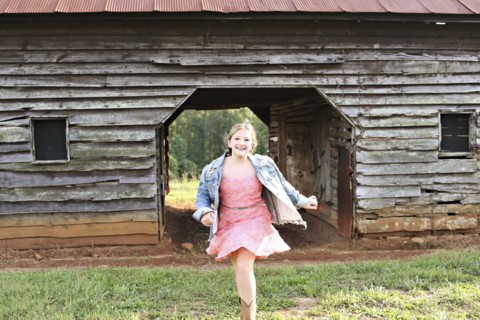 Smiling girl running near barn on rural farm