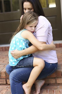 Close up of mother comforting daughter on front stoop