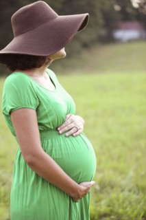 Pregnant Caucasian woman holding belly in field