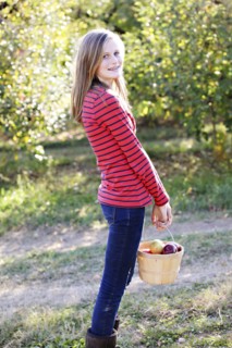 Caucasian girl picking fruit in orchard