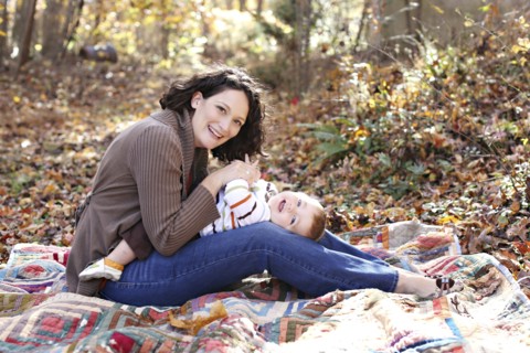 Mother and baby daughter playing on blanket in forest