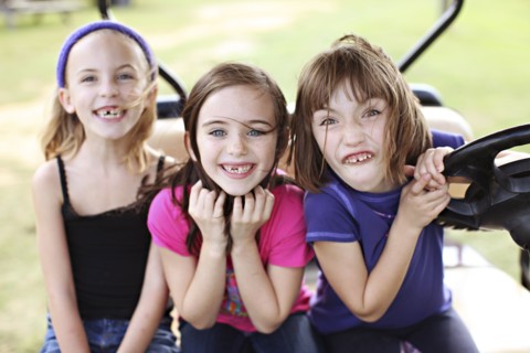 Caucasian girls making faces in golf cart