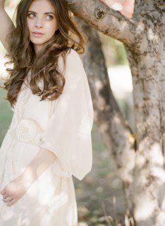 Bride in wedding dress standing under tree