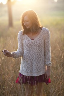 Girl standing in tall grass in rural field