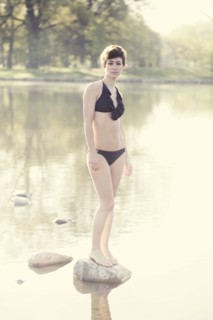 Woman in lingerie standing on rock in still pond