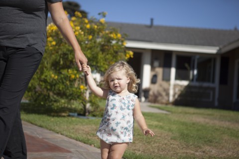 Mother and daughter walking on sidewalk