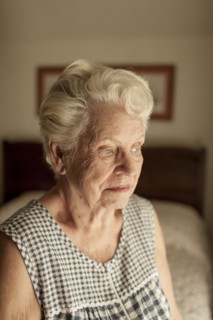 Pensive older woman sitting on bed