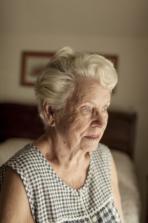 Pensive older woman sitting on bed