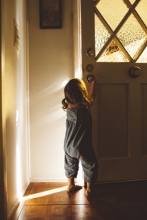 Hispanic preschooler girl opening front door