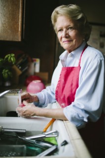 Older woman washing dishes in kitchen sink